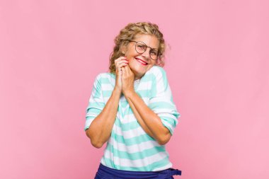 Orta yaşlı bir kadın aşık ve sevimli görünüyor. Sevimli ve mutlu. Romantik bir şekilde gülümsüyor.