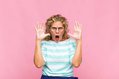 Orta yaşlı bir kadın elleri havada bağırıyor. Öfkeli, sinirli, stresli ve üzgün.