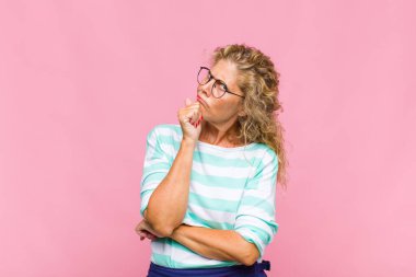 Orta yaşlı kadın düşünüyor, kuşkulu ve şaşkın hissediyor, farklı seçeneklerle, hangi kararı vereceğini merak ediyor.