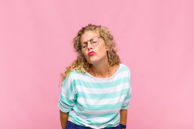 Orta yaşlı bir kadın tatlı, eğlenceli, mutlu, sevimli bir yüz ifadesiyle dudaklarını birbirine bastırıyor.