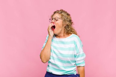 Orta yaşlı bir kadın sabahın erken saatlerinde uyanıyor, uykulu, yorgun ve sıkkın görünüyor.