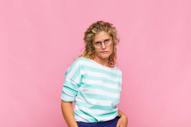 Orta yaşlı bir kadın mutlu, mutlu, kendinden emin ve rahat bir ifadeyle neşeli bir şekilde gülümsüyor.