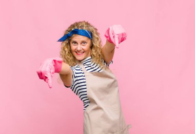 Orta yaşlı bir kadın mutlu ve kendinden emin, kamerayı iki eliyle gösteriyor ve gülüyor, seni hizmetçi olarak seçiyor.