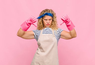 Orta yaşlı bir kadın üzgün, hayal kırıklığına uğramış ya da kızgın görünüyor. Anlaşmazlıkta baş parmaklarını gösteriyor. Hayal kırıklığına uğramış hizmetçi konseptini hissediyor.