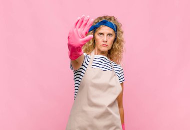 Orta yaşlı kadın ciddi, sert, hoşnutsuz ve kızgın görünüyor. Avuç içini açıp jest yapmayı kesiyor.