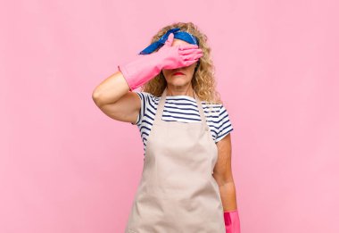 Orta yaşlı bir kadın tek eliyle gözlerini kapatıyor korkmuş ya da endişeli, merak ediyor ya da körü körüne sürpriz bir hizmetçi konseptini bekliyor.