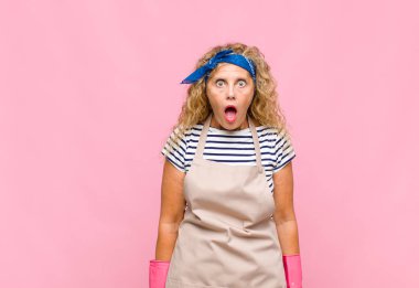 Orta yaşlı kadın çok şaşırmış ya da şaşkın görünüyor, ağzı açık bakıyor ve 