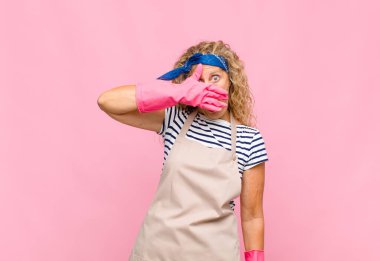 Orta yaşlı bir kadın şok olmuş, korkmuş ya da korkmuş görünüyor. Yüzü elle örtülmüş ve hizmetçinin parmaklarının arasına bakıyor.