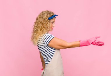Orta yaşlı bir kadın gülümsüyor, sizi selamlıyor ve başarılı bir anlaşma için el sıkışmayı teklif ediyor. İşbirliği konsepti ev kadını konsepti.