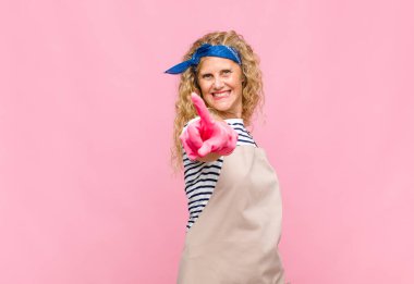 Orta yaşlı bir kadın gururla gülümsüyor ve gururla bir numaralı pozu veriyor. Lider hizmetçi konsepti gibi hissediyor.