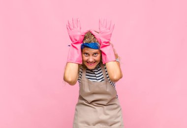 Orta yaşlı bir kadın gülümsüyor ve arkadaş canlısı görünüyor, onuncu ya da onuncu numarayı gösteriyor, eli önde, temizlikçi konseptini sayıyor.