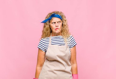 Orta yaşlı bir kadın üzgün, üzgün ya da kızgın ve olumsuz bir tavır takınıyor, anlaşmazlık içindeki hizmetçi kavramına ters düşüyor.