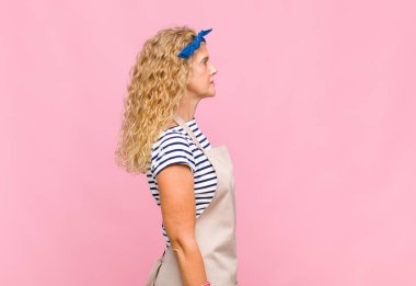 Profil görünümlü orta yaşlı bir kadın ileride bir yer kopyalamak istiyor. Düşünüyor, hayal ediyor ya da hayal kuruyor.