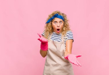 Orta yaşlı kadın ağzı açık ve şaşkın, şaşırmış ve şaşırmış inanılmaz bir sürpriz ev hanımı konseptiyle