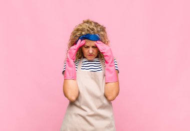 Stresli ve hayal kırıklığına uğramış görünen orta yaşlı kadın, baş ağrısı ve sorunlu ev hanımı kavramı ile baskı altında çalışıyor.