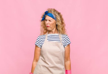 Orta yaşlı bir kadın mutlu ve arkadaş canlısı görünüyor, gülümsüyor ve sana olumlu bir tavırla göz kırpıyor.