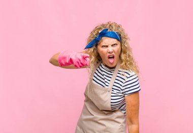 Orta yaşlı bir kadın kızgın agresif bir ifadeyle kameraya bakıyor. Öfkeli, çılgın bir patron-hizmetçi kavramı gibi görünüyor.