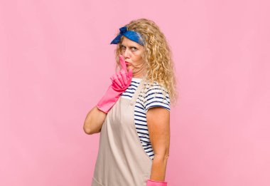 Orta yaşlı bir kadın sessizlik ve sessizlik istiyor, parmaklarını ağzının önüne uzatıp 