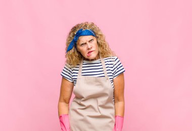 Orta yaşlı kadın şaşkın ve şaşkın görünüyor. Sinirli bir jestle dudağını ısırıyor. Sorunlu hizmetçi kavramının cevabını bilmiyor.