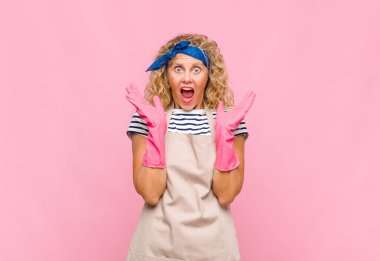 Orta yaşlı bir kadın mutlu ve heyecanlı görünüyor. Beklenmedik bir sürprizle şoke oldu. İki eli de açık.