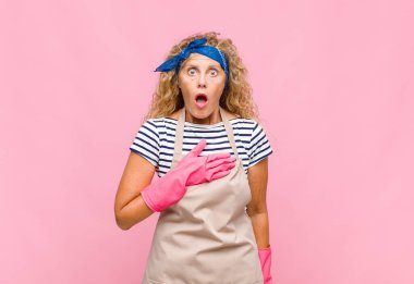 Orta yaşlı bir kadın şaşkın ve şaşırmış hissediyor, gülümsüyor, el ele tutuşuyor, o kişi olmaktan mutlu ya da minnettarlık göstermekten mutlu.