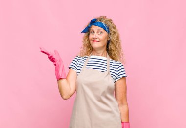 Orta yaşlı bir kadın kendini mutlu, şaşırmış ve neşeli hisseder. Pozitif bir tavırla gülümser. Bir çözüm ya da ev hanımı kavramının farkına varır.