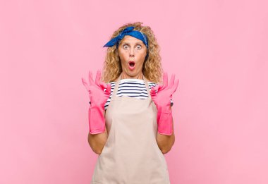 Orta yaşlı kadın şaşkın, şaşırmış ve şaşırmış hissediyor. Onaylıyor. İki elini de temizlikçi kavramına uygun hale getiriyor.