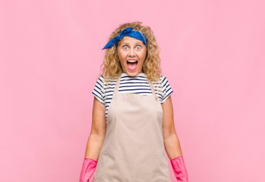 Orta yaşlı kadın mutlu ve hoş bir şekilde şaşırmış görünüyor. Büyülenmiş ve şok olmuş bir ifadeyle ev hanımı kavramından etkilenmiş.