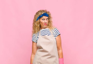 Orta yaşlı bir kadın kendini şaşkın ve kuşkulu hisseder, merak eder ya da karar vermeye çalışır.