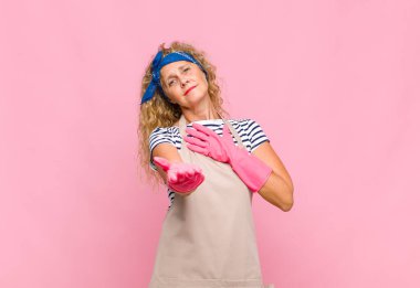 Orta yaşlı bir kadın kendini mutlu ve aşık hissediyor, bir eli kalbinin yanında gülümsüyor ve diğer eli de hizmetçi konseptinde uzanıyor.