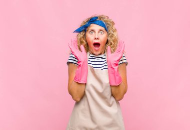 Orta yaşlı bir kadın beklenmedik bir ev hanımı konsepti yüzünden şaşkın ve heyecanlı, gülen, şaşkın ve mutlu hissediyor.