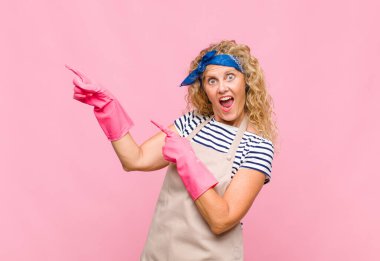 Orta yaşlı kadın mutlu ve şaşırmış hissediyor, şok olmuş bir ifadeyle gülümsüyor ve yan hizmetçi kavramına işaret ediyor.