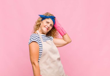 Orta yaşlı bir kadın neşeli ve sıradan bir şekilde gülümsüyor, pozitif, mutlu ve kendine güvenen bir hizmetçi konseptiyle kafa kafaya gidiyor.