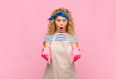 Orta yaşlı bir kadın şaşkın, ağzı açık ve şaşırmış, inançsızlık ve sürpriz ev hanımı kavramına bakıyor ve işaret ediyor.