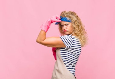 Orta yaşlı kadın kendini mutlu, tatmin olmuş ve güçlü hissediyor, kaslı ve formda, spor salonu hizmetçisi konseptinden sonra güçlü görünüyor.