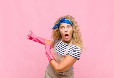 Orta yaşlı bir kadın şaşkın ve şaşırmış hissediyor. Yanındaki fotokopi alanını işaret ediyor. Şaşırmış, ağzı açık, ev hanımı gibi görünüyor.