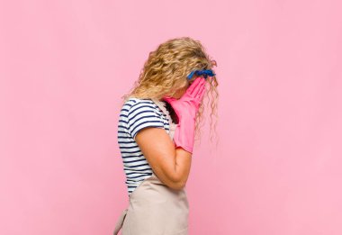 Orta yaşlı bir kadın, üzgün, hayal kırıklığına uğramış bir bakışla gözlerini kapatıyor. Ağlıyor, yan gözle bakıyor.