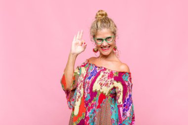 Orta yaşlı bir kadın mutlu, rahat ve tatmin olmuş hissediyor. Onayını iyi bir hareketle gösteriyor.