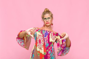 Orta yaşlı bir kadın üzgün, hayal kırıklığına uğramış ya da kızgın görünüyor. Anlaşmazlıkta baş parmağını gösteriyor. Hayal kırıklığına uğramış hissediyor.