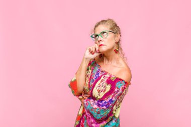 Orta yaşlı kadın, yoğun bakışlı, şüpheli bir ifadeyle merak ediyor, yukarı ve yana bakıyor