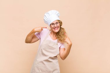 Orta yaşlı bir fırıncı kendi gülüşünü, pozitif, rahat, tatmin olmuş tavrını, kendine gülerek gösteriyor.