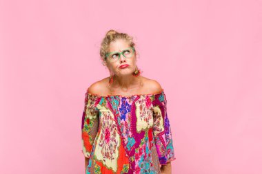 Orta yaşlı kadın şaşkın ve şaşkın görünüyor, merak ediyor veya bir sorunu çözmeye çalışıyor veya düşünüyor.