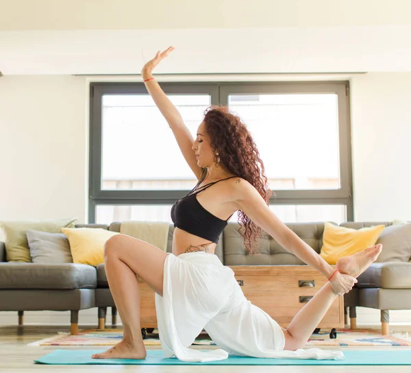Evde yoga yapan genç ve güzel bir kadın. Evde dinlenme ve antrenman.