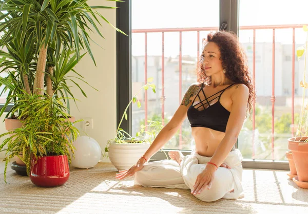 Evde yoga yapan genç ve güzel bir kadın. Evde dinlenme ve antrenman.