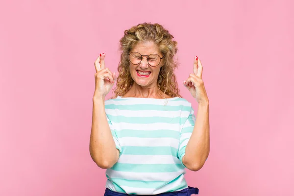 Mujer Mediana Edad Sonriendo Ansiosamente Cruzando Ambos Dedos Sintiéndose Preocupada —  Fotos de Stock