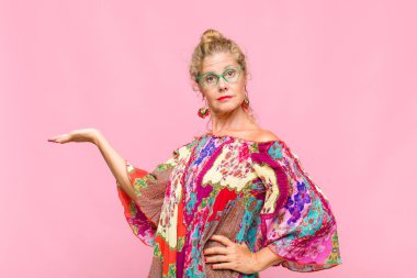 Orta yaşlı kadın gülümsüyor, kendinden emin, başarılı ve mutlu hissediyor, fotokopi alanında fikir veya konsept gösteriyor.