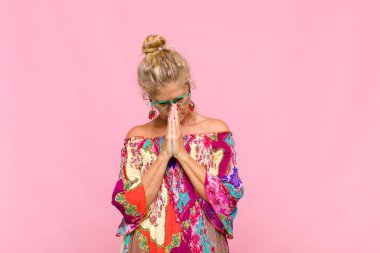 Orta yaşlı bir kadın endişeli, umutlu ve dindar. Avuçlarına bastırılmış, af dileyen sadık bir şekilde dua ediyor.