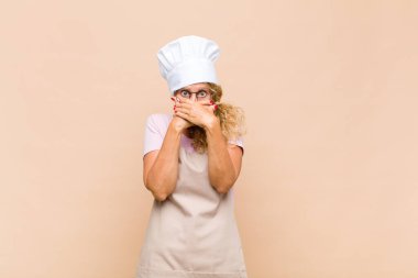 Orta yaşlı fırıncı elleri ile ağzını kapatan şok olmuş, şaşırmış bir ifadeyle, sır saklayan ya da 