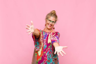 Orta yaşlı bir kadın neşeyle gülümsüyor sıcak, dostça, sevgi dolu bir kucak veriyor, mutlu ve sevimli hissediyor.