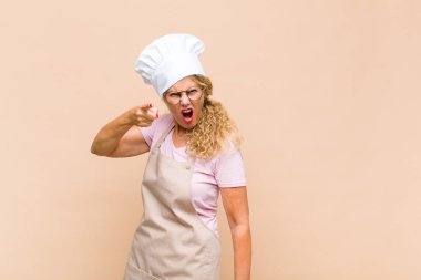 Orta yaşlı bir fırıncı kızgın agresif bir ifadeyle kameraya bakıyor. Öfkeli, çılgın bir patron gibi görünüyor.